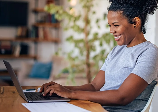 A woman smiling while typing on a computer